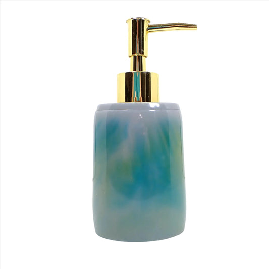 Side view of the handmade resin soap dispenser. It is oval shaped with a wider bottom. There are marbled shades of teal blue, green, and gray resin. The pump in the photo is gold in color.