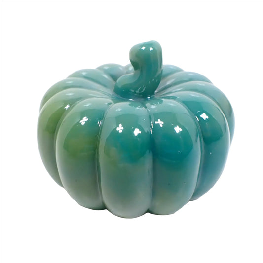 Side view of the small handmade resin pumpkin. It has marbled shades of teal blue, green, and gray.