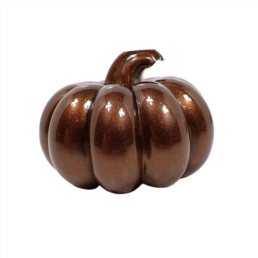 Side view of the small handmade resin pumpkin. It is a pearly dark brown in color.