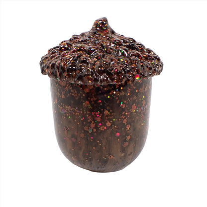 Side view of the handmade resin acorn trinket box jar. The lid and bottom are dark pearly brown in color with chunky iridescent glitter throughout.