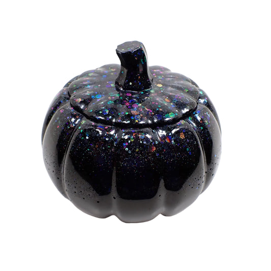 Side view of the handmade pumpkin trinket box decorative jar. It is black in color with multi color iridescent chunky glitter at the top.