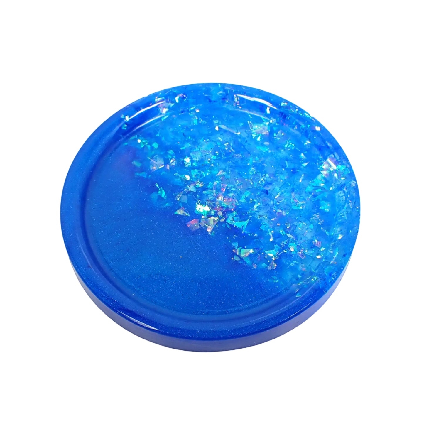 Angled view of the small handmade resin round trinket dish. It has pearly bright ocean blue color resin on one side and iridescent blue glitter flakes on the other side.