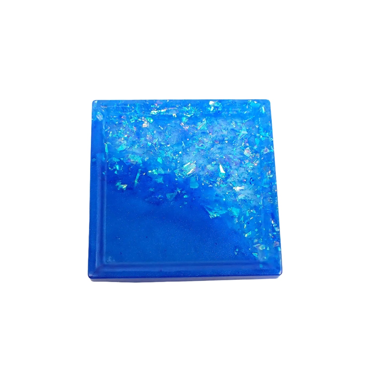 Top view of the small handmade square resin trinket dish. There is bright pearly ocean blue resin on half the piece at a diagonal and the other side has iridescent blue glitter flakes.