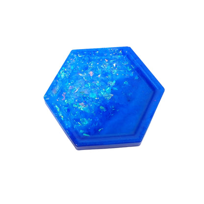 Top view of the handmade geometric hexagon small resin trinket dish. It has pearly ocean blue resin on one side and iridescent blue glitter flakes on the other.