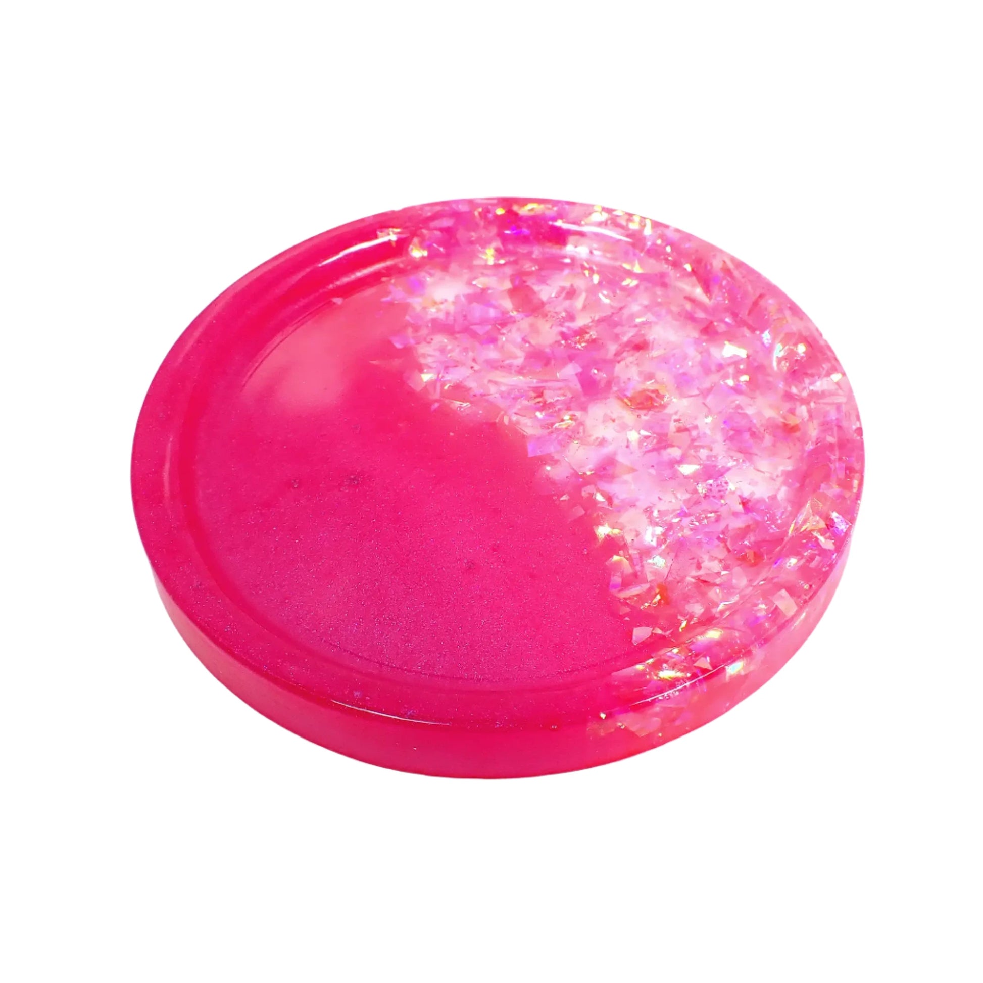 Angled view of the small round handmade resin trinket dish tray. There is pearly bright pink resin on one side and iridescent pink glitter flakes on the other.