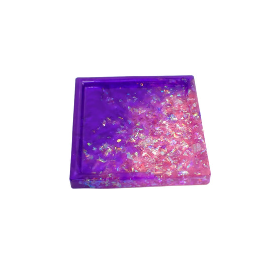 Handmade square resin trinket dish with iridescent flakes. It has an area of pearly purple resin and an area of iridescent flakes that appear a light lilac purple to pink color.