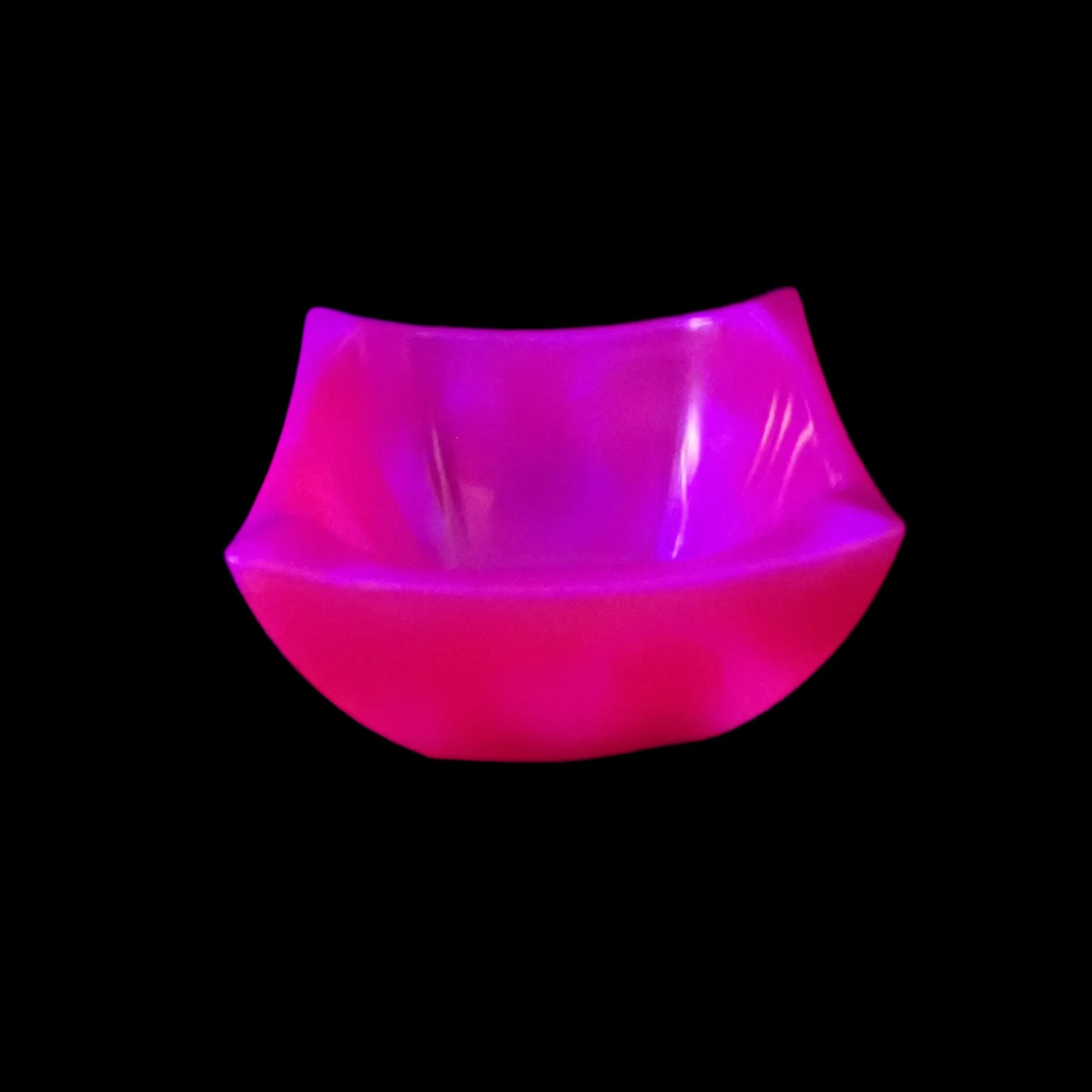 Photo of the handmade angled square decorative bowl showing how the neon pink fluoresces under a UV light.