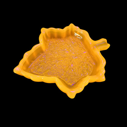 Photo showing how the handmade neon orange resin decorative leaf tray fluoresces under a UV light.