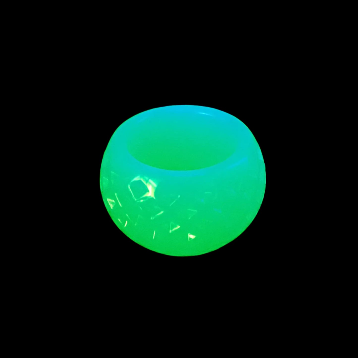 Photo showing how the handmade small neon green resin decorative bowl with indented diamond pattern fluoresces under a UV light.