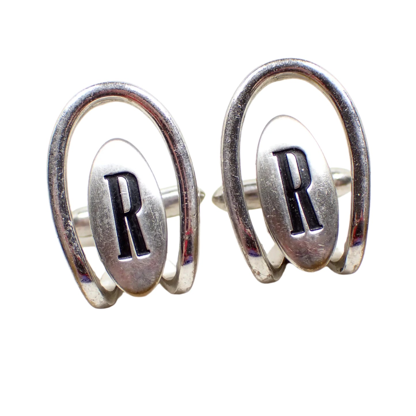 Front view of the Swank 1960's Mid Century vintage letter cufflinks. The metal is silver tone in color. They have an open arch style design over an oval that has a black painted recessed initial R in the middle.