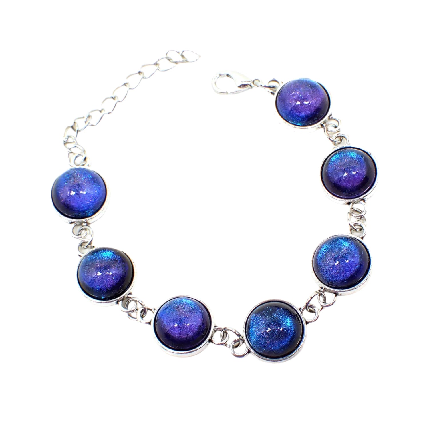 Top view of the handmade link bracelet. The metal is silver tone in color with lobster claw clasp. There are seven round link areas with domed resin cabs that color shift from blue to purple depending on how the light hits it.