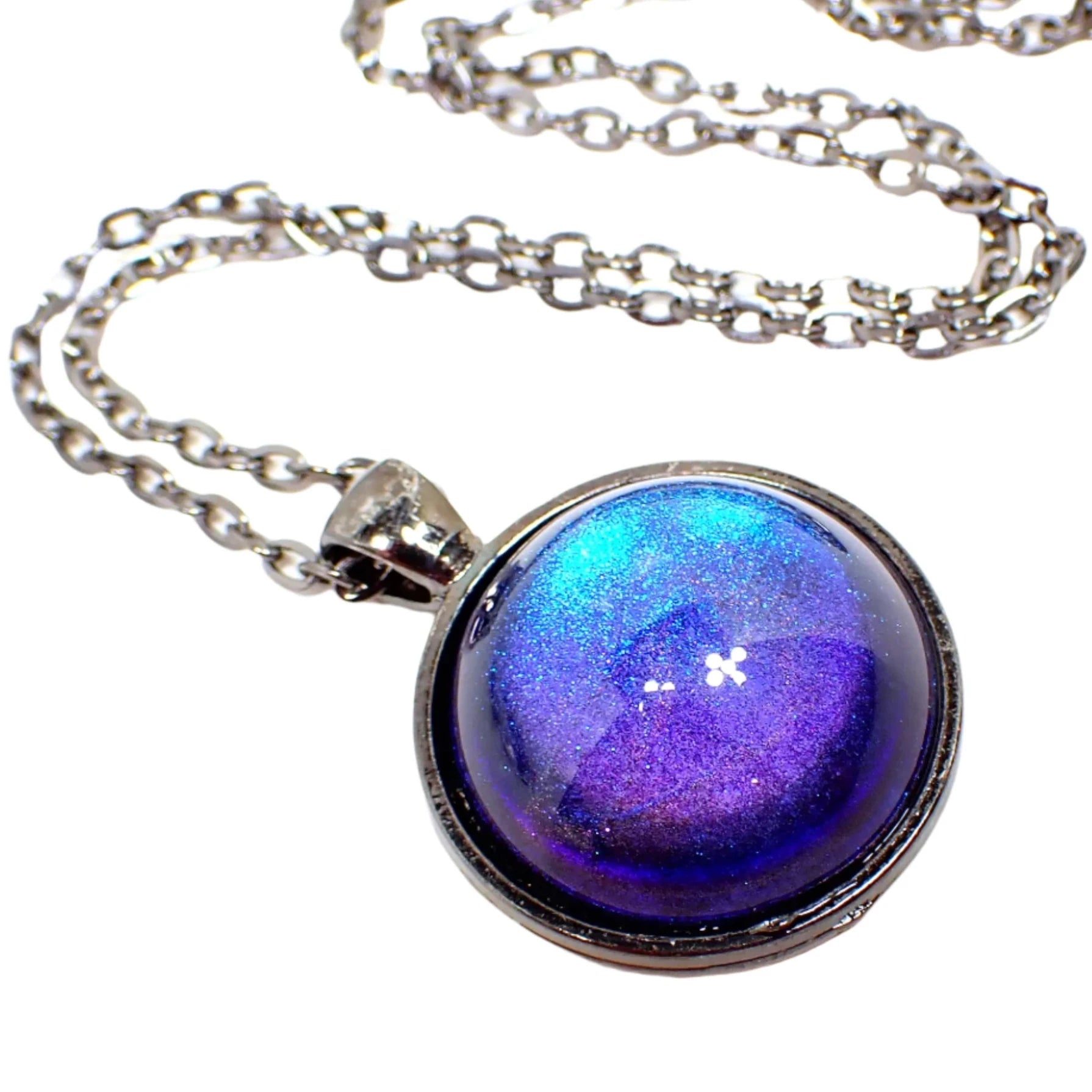 Enlarged view of the handmade color shift round resin pendant necklace. The metal is gunmetal gray in color. The round pendant has a domed round cab with a color shift design that goes from blue to purple depending on how the light is hitting it.