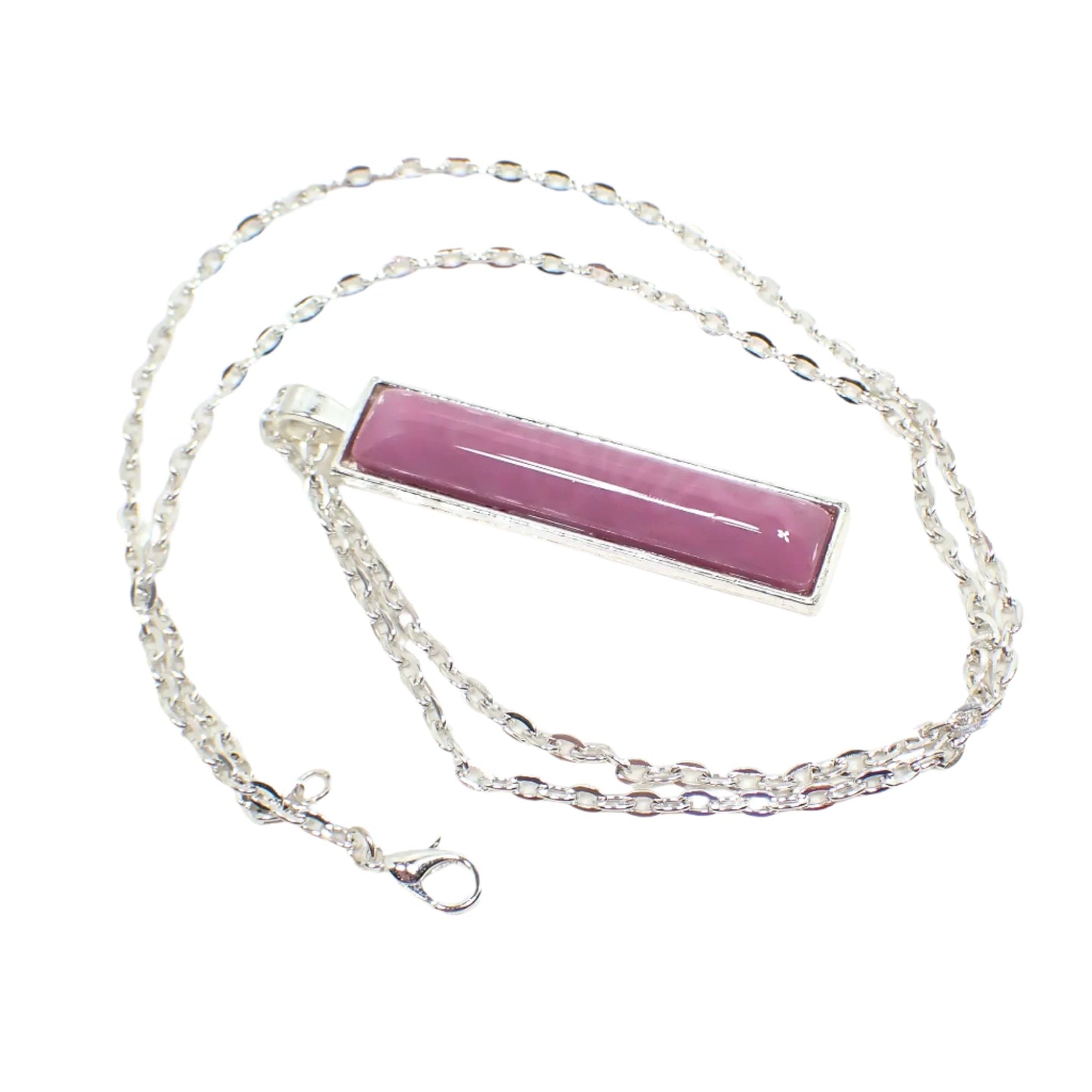 Angled view of the handmade bar pendant. The metal is silver tone in color. It has a cable chain with lobster claw clasp and a long rectangle bar shaped pendant. The pendant has a domed handmade resin cab with marbled shades of rose pink.