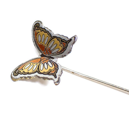 Enlarged view of the retro vintage Reed and Barton Damascene lapel stick pin. The pin itself is silver tone color. The top has a butterfly design with silver, gold, and copper plated areas. There is black enamel defining the edges of the butterfly design.