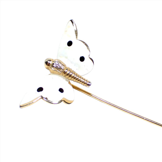 Enlarged view of the Mid Century vintage butterfly stick pin. The metal is gold tone in color. The wings of the butterfly are white enameled with 4 black enameled spots.
