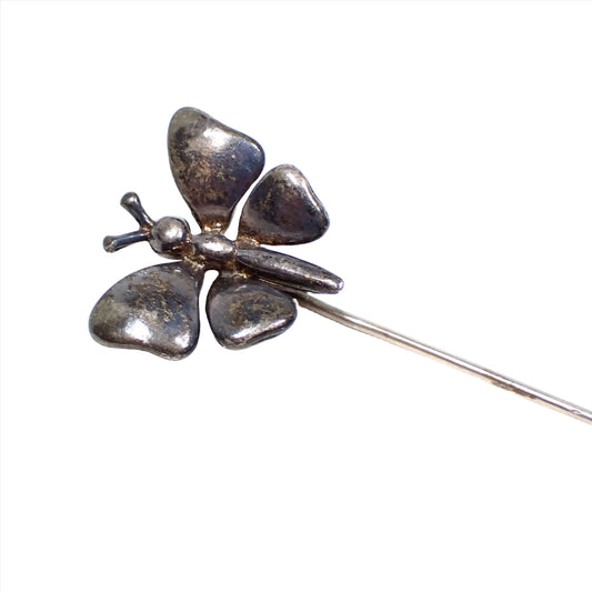 Enlarged view of the 1940's Mid Century vintage lapel stick pin. The sterling silver has darkened to a dark gray in color. The top has a butterfly shape with four separate wings, a body, a head, and antennae. 