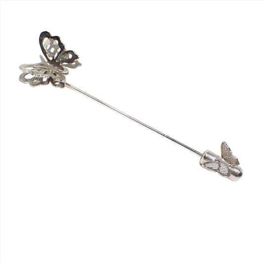 Full view of the Mid Century vintage butterflies stick pin. The metal is silver tone in color. The top has a butterfly with a cut out double wing style design. The clutch on the bottom of the pin has a smaller sized textured butterfly on it.