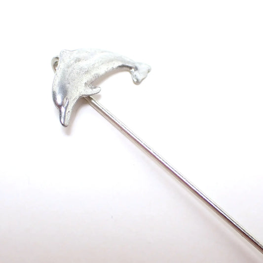 Enlarged view of the retro vintage dolphin stick pin. It is silver tone in color and has a dolphin shape at the top.