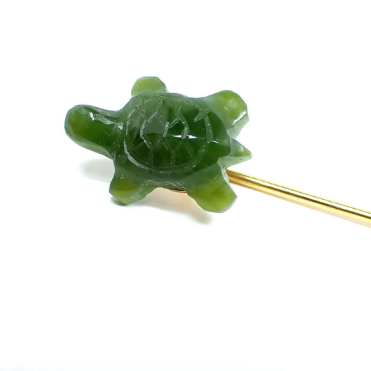 Enlarged view of the Mid Century vintage carved jade stick pin. The metal is gold tone in color. The top has a carved jade turtle that is a lovely shade of green.