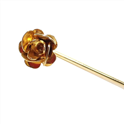 Enlarged photo of the top of the Mid Century vintage tiny flower pin. The metal is gold in color. The top has a flower design with metal rounded flower petals forming the flower. 