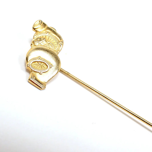 Enlarged photo of the top of the retro vintage stick lapel pin. The metal is matte gold tone in color. The top has a design that looks like two centrifugal fans pointing in opposite directions with a piece of equipment in between. 