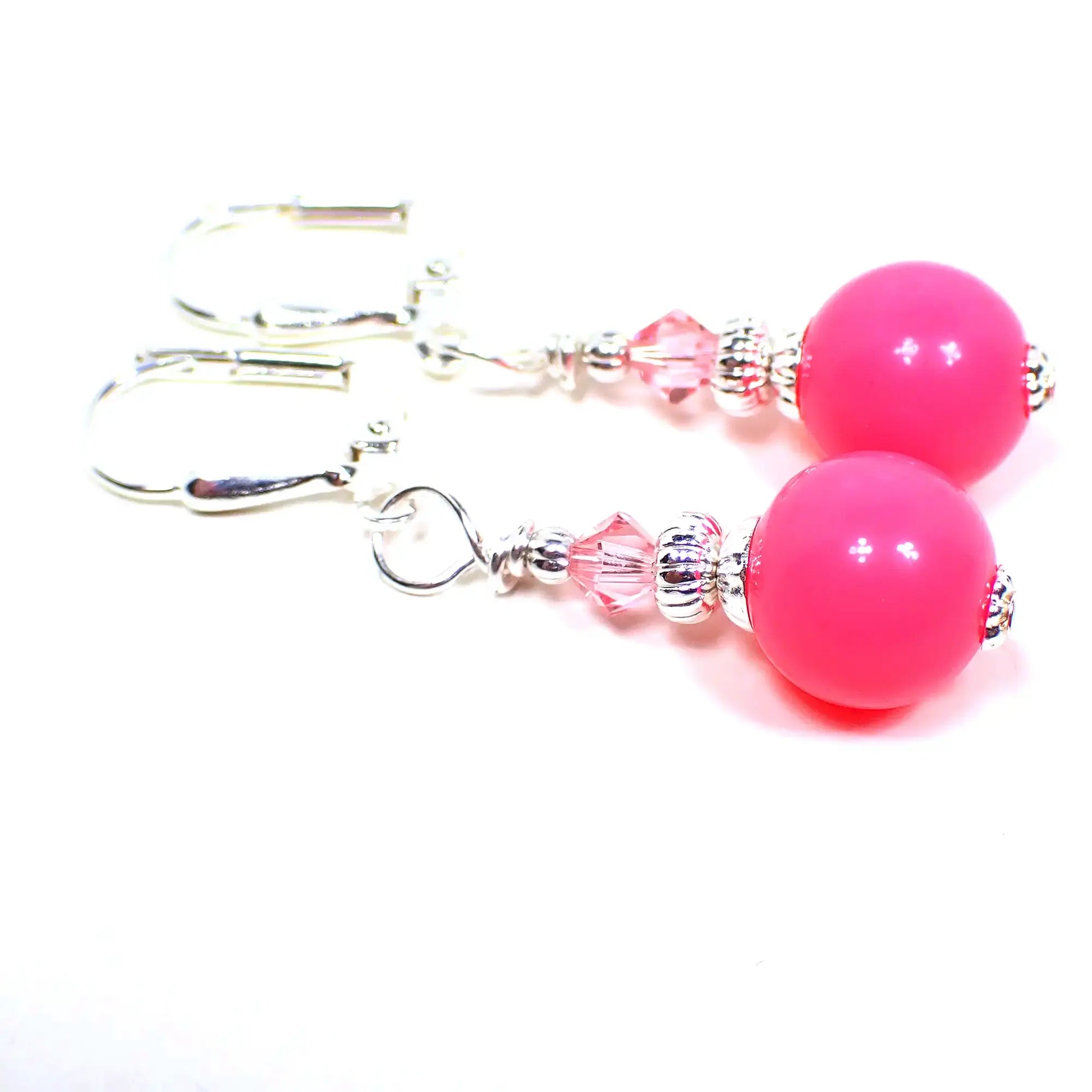 Top view of the handmade small drop earrings with vintage acrylic beads. The metal is bright silver in color. There is a faceted glass crystal bead in light pink at the top. The bottom acrylic beads are round ball shaped and are bright pink in color.
