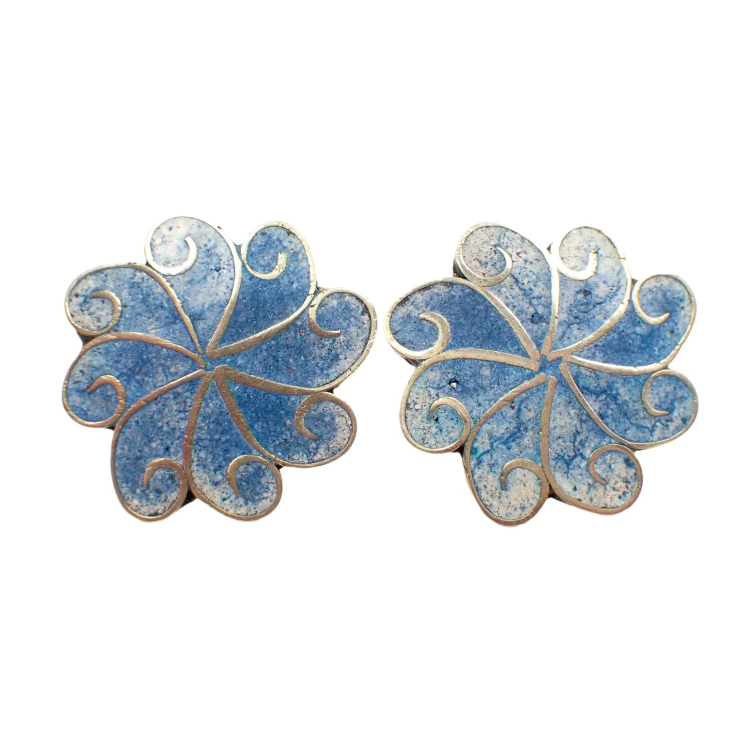 Front view of the vintage Alpaca screw back earrings.  They are shaped like a pinwheel with curled ends and silver tone color metal. The in between areas have a crushed stone inlay in shades of light blue and white.