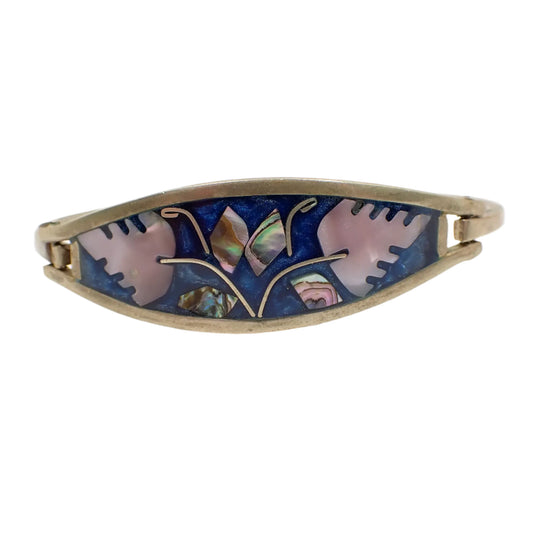 Front view of the vintage Alpaca hinged bangle bracelet. The metal is silver tone in color. The front has a leaf design with small inlaid pieces of abalone shell for the smaller leaves and inlaid mother of pearl shell for the larger leaves.