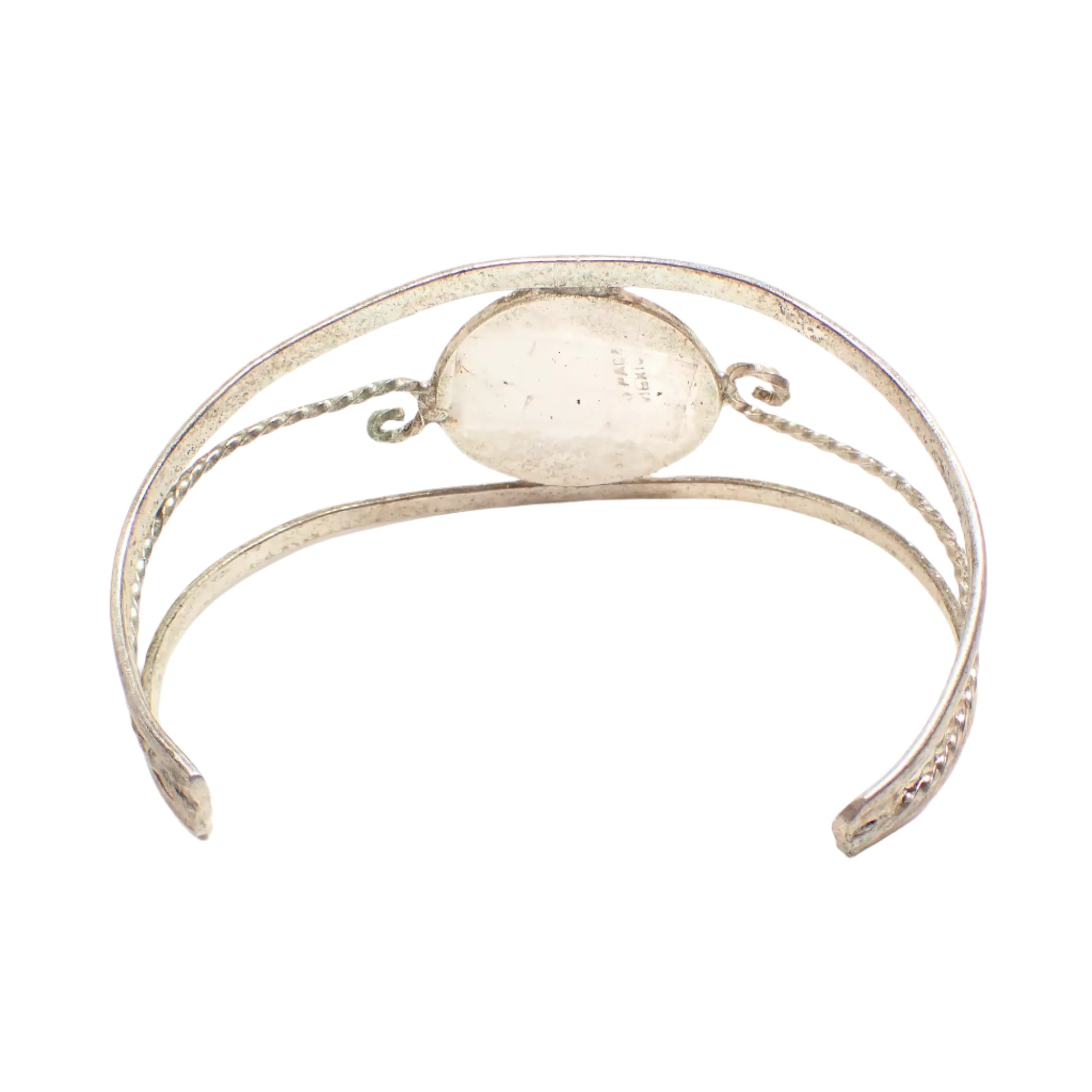 Back view of the vintage Alpaca cuff bracelet. The metal is silver tone in color. Part of the Alpaca Mexico marking can be seen on the inside area of the cuff.