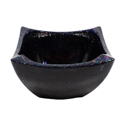 Side view of the handmade resin angled square decorative bowl. It is black with iridescent black glitter mostly around the top edge area.