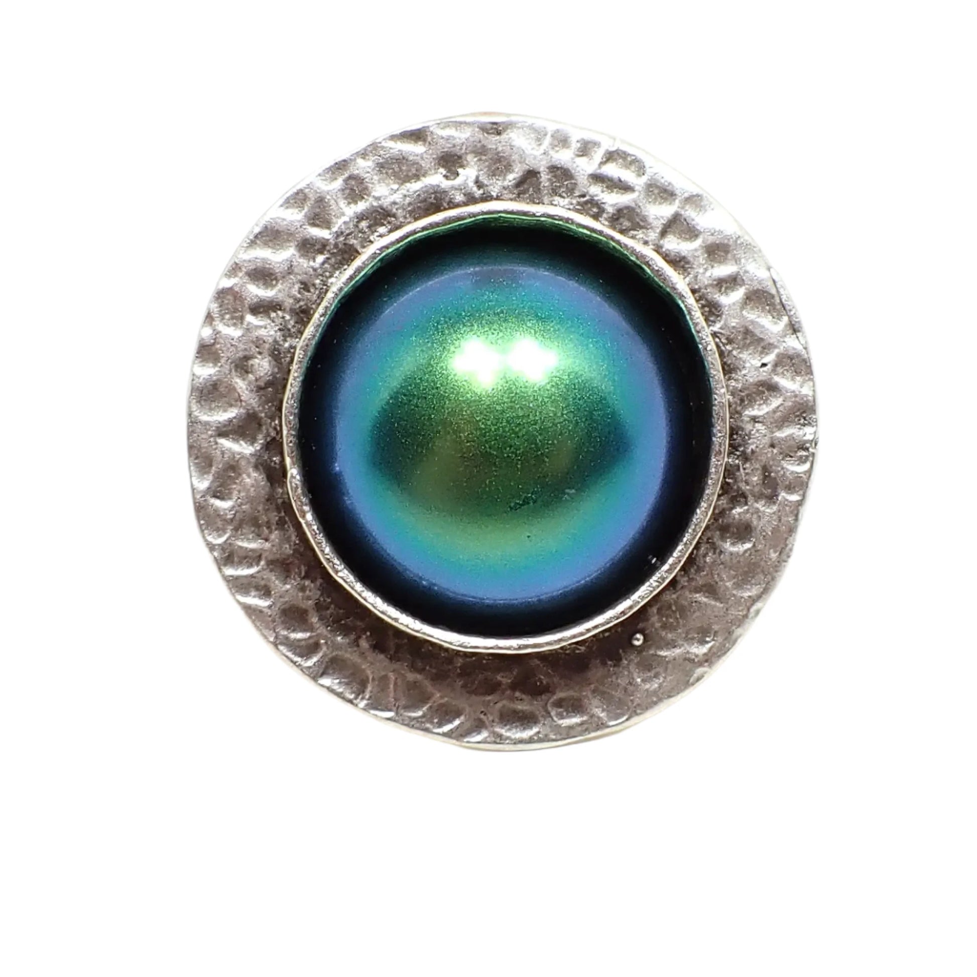 Front view of the hammered ring with color shift cab. The metal is antiqued silver in color. There is a hammered edge around the outside of the ring. The middle has a large domed round resin cab with color shift resin that goes between shades of blue and green.