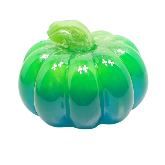 Angled view of the small shiny pumpkin decoration. The stem has pearly green resin. The top part of the pumpkin has bright neon green resin and the bottom has a teal blue neon resin. 