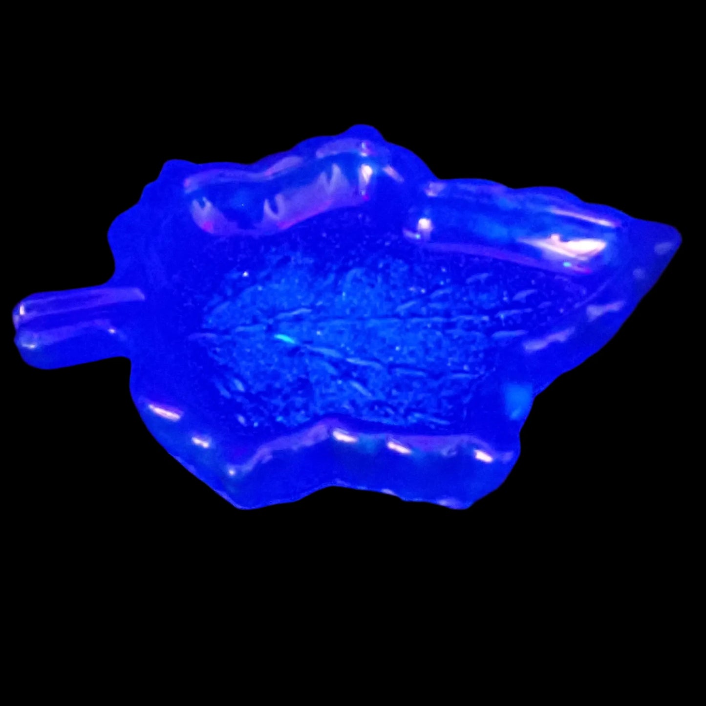 Photo of the blue leaf trinket dish under a UV light to show how it fluoresces blue.