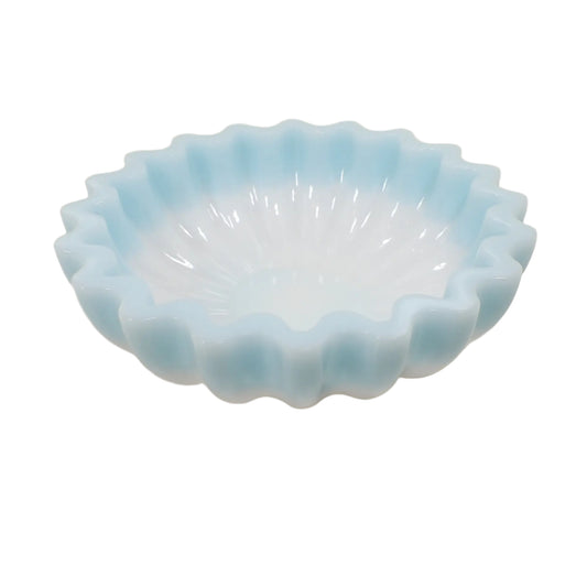 Angled view of the handmade scalloped bowl. It has a light pastel blue resin towards the top of the bowl and white on bottom. The edge has a rounded wavy design.