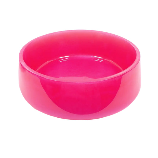 Angled side view of the handmade resin decorative bowl. It has a large round shape with a slightly flared out bottom. The resin is shiny and opaque in a bright pearly hot pink color. Would be great as a table centerpiece with other decor set inside it.