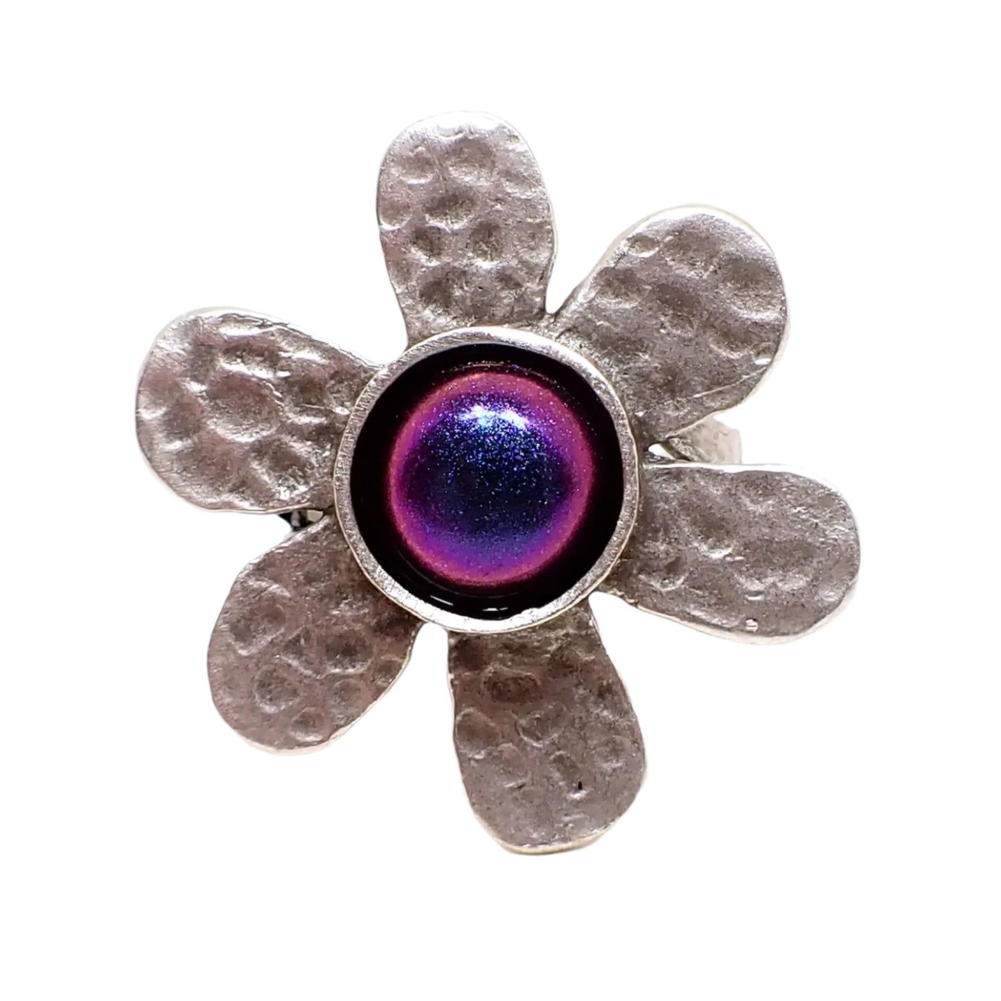 Front view of the color shift flower ring. The metal is antiqued silver in color. There are six rounded hammered petals around the edge. The middle has a domed round color shift resin cab that shows different colors depending on how the light is hitting it.