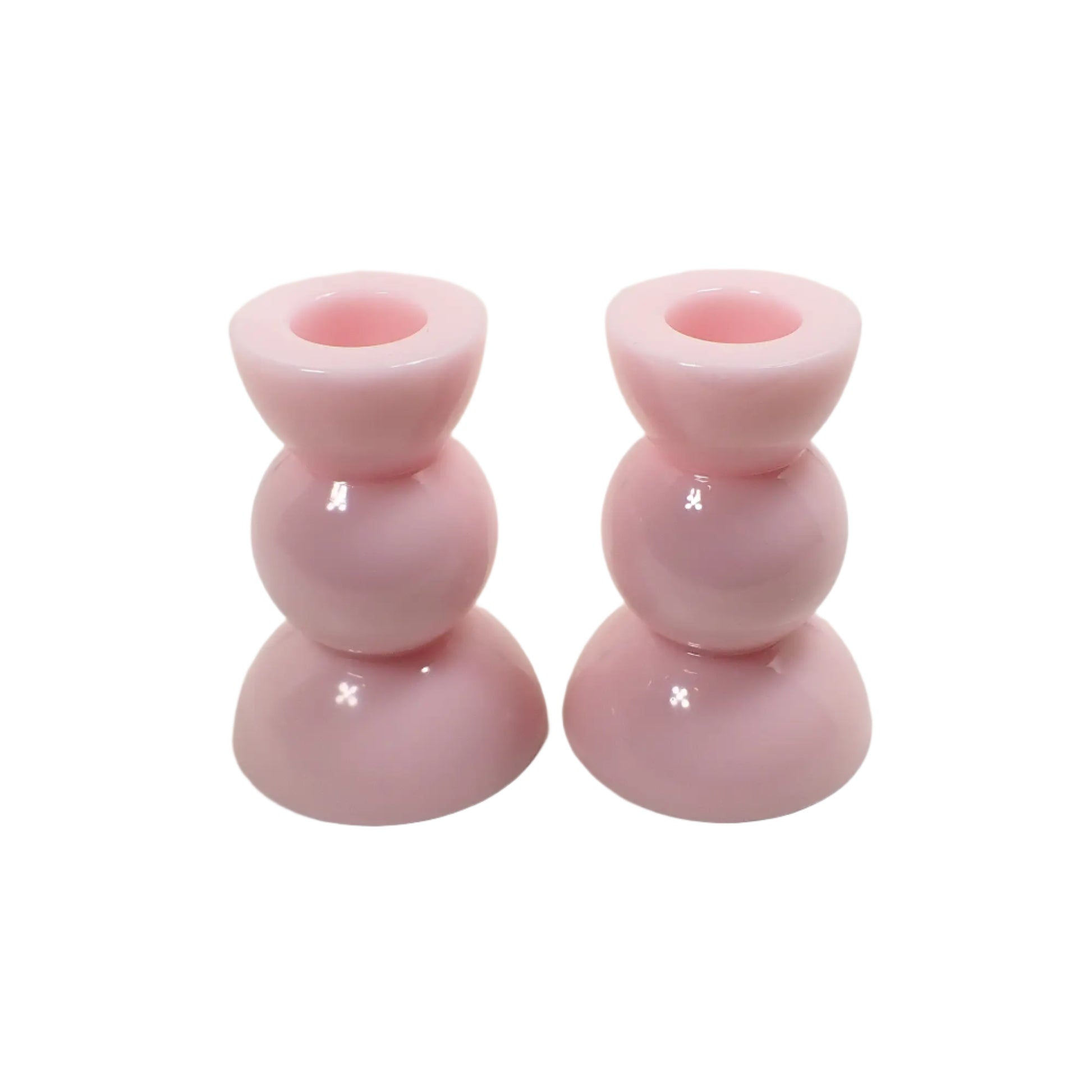 Angled view of the handmade resin candle holders. They are a light cotton candy pink in color. 