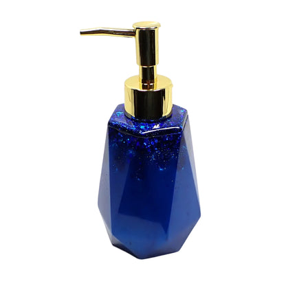 Side view of the handmade resin soap dispenser. It has dark ocean blue resin with dark ocean blue glitter towards the top. It has a faceted design that's flared at the bottom and tapered at the top.