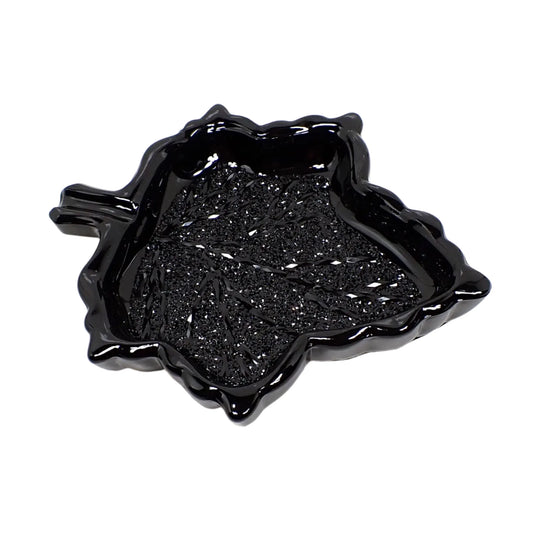 Angled view of the Goth black resin leaf trinket dish showing the inside area where it sparkles from the crystal like faceted design. The leaf is shaped like a decorative dish with raised sides.