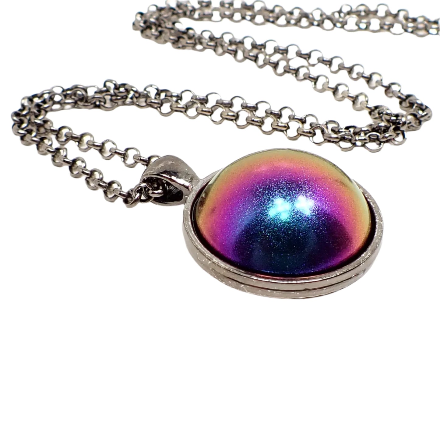 Enlarged close up of the pendant showing the round gunmetal setting and the domed round resin cab. The resin is matte metallic and shades of blue, pink, purple, and yellow are showing.