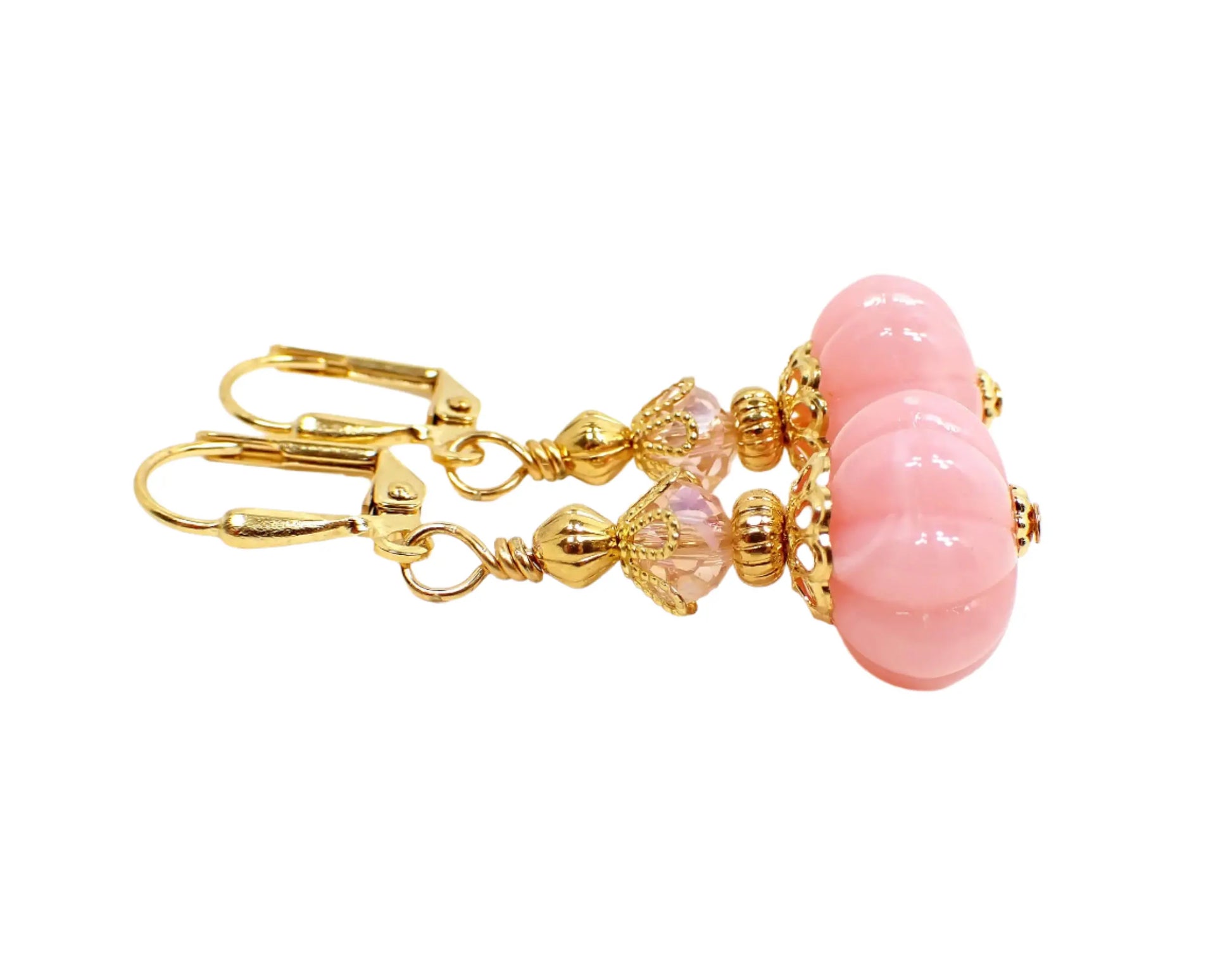 Side view of the handmade light pink pumpkin shaped drop earrings. Here the swirls of white can be seen on the bottom vintage beads. The facets can also be seen on the top glass crystal beads.