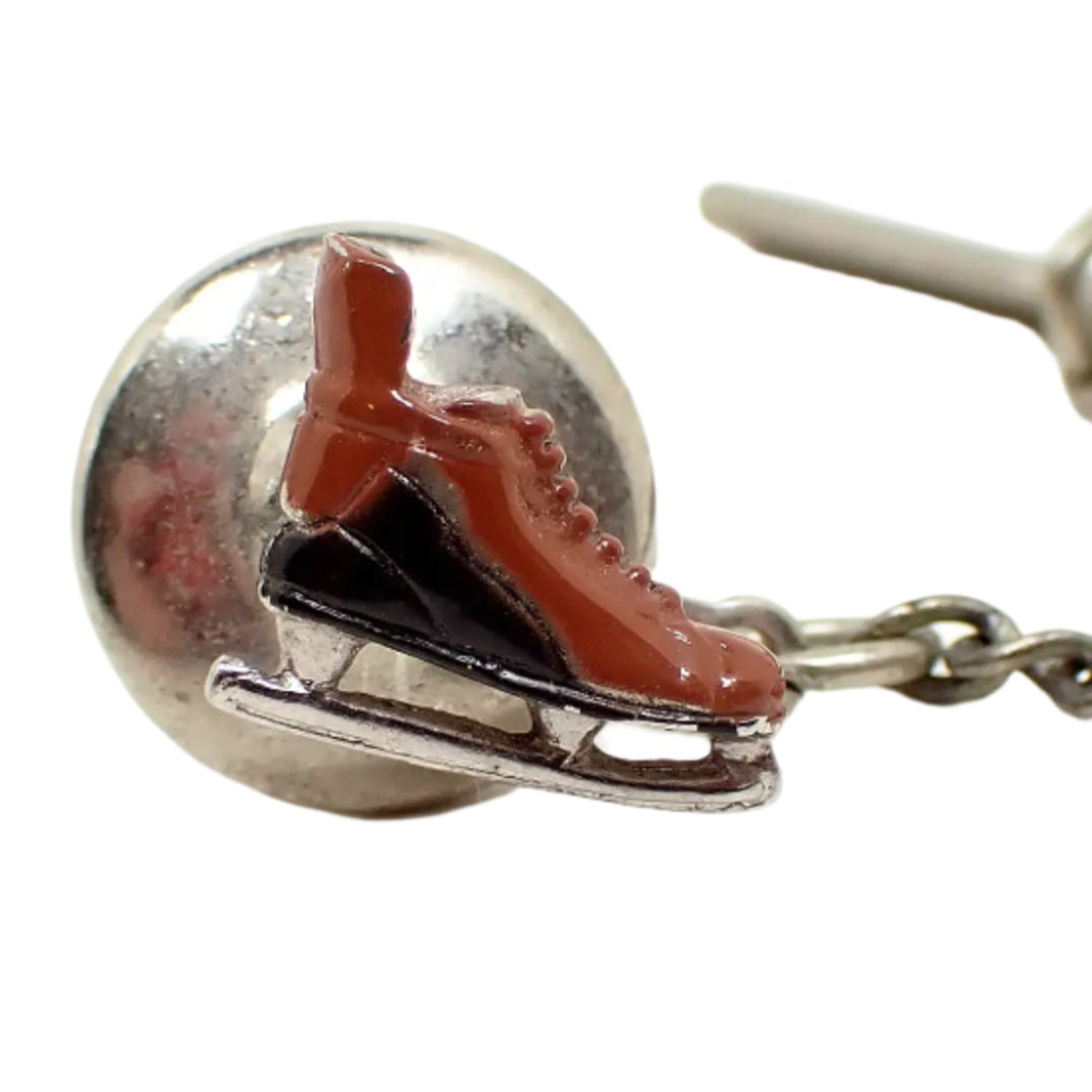 Enlarged view of the Swank vintage ice skate tie tack. The metal is silver tone in color and the ice skate is enameled with reddish brown and black enamel. 