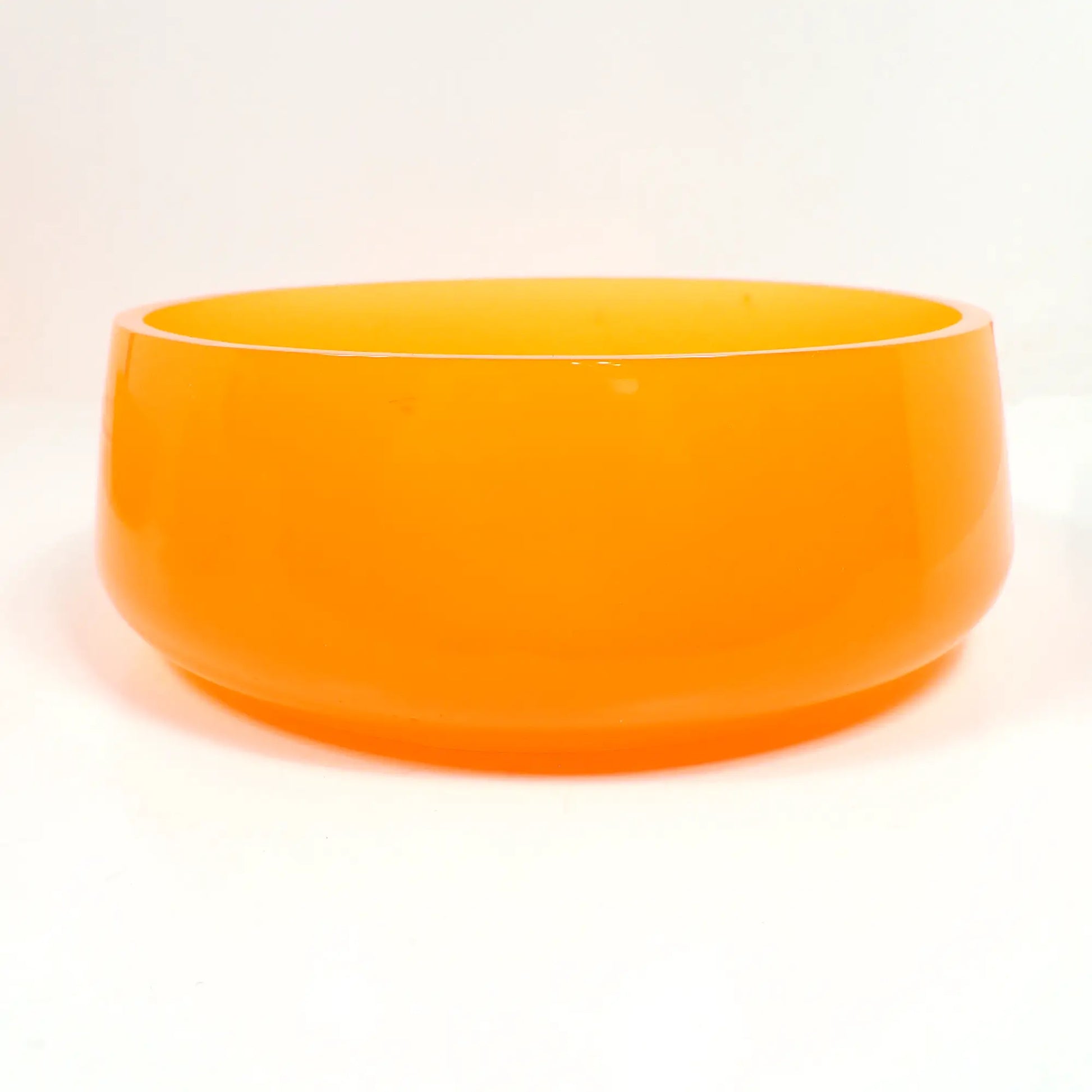 Side view of the handmade neon orange resin decorative bowl. It is round with a slight flared out bottom. The resin is shiny and semi translucent in a bright neon orange color. The top edge is flat and smooth. Great for a table centerpiece, as a succulent pot, or just to add to your fluorescent decor.