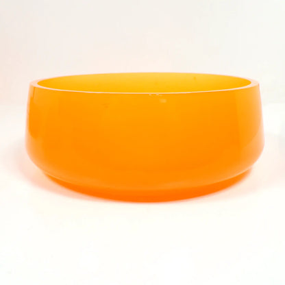 Side view of the handmade neon orange resin decorative bowl. It is round with a slight flared out bottom. The resin is shiny and semi translucent in a bright neon orange color. The top edge is flat and smooth. Great for a table centerpiece, as a succulent pot, or just to add to your fluorescent decor.