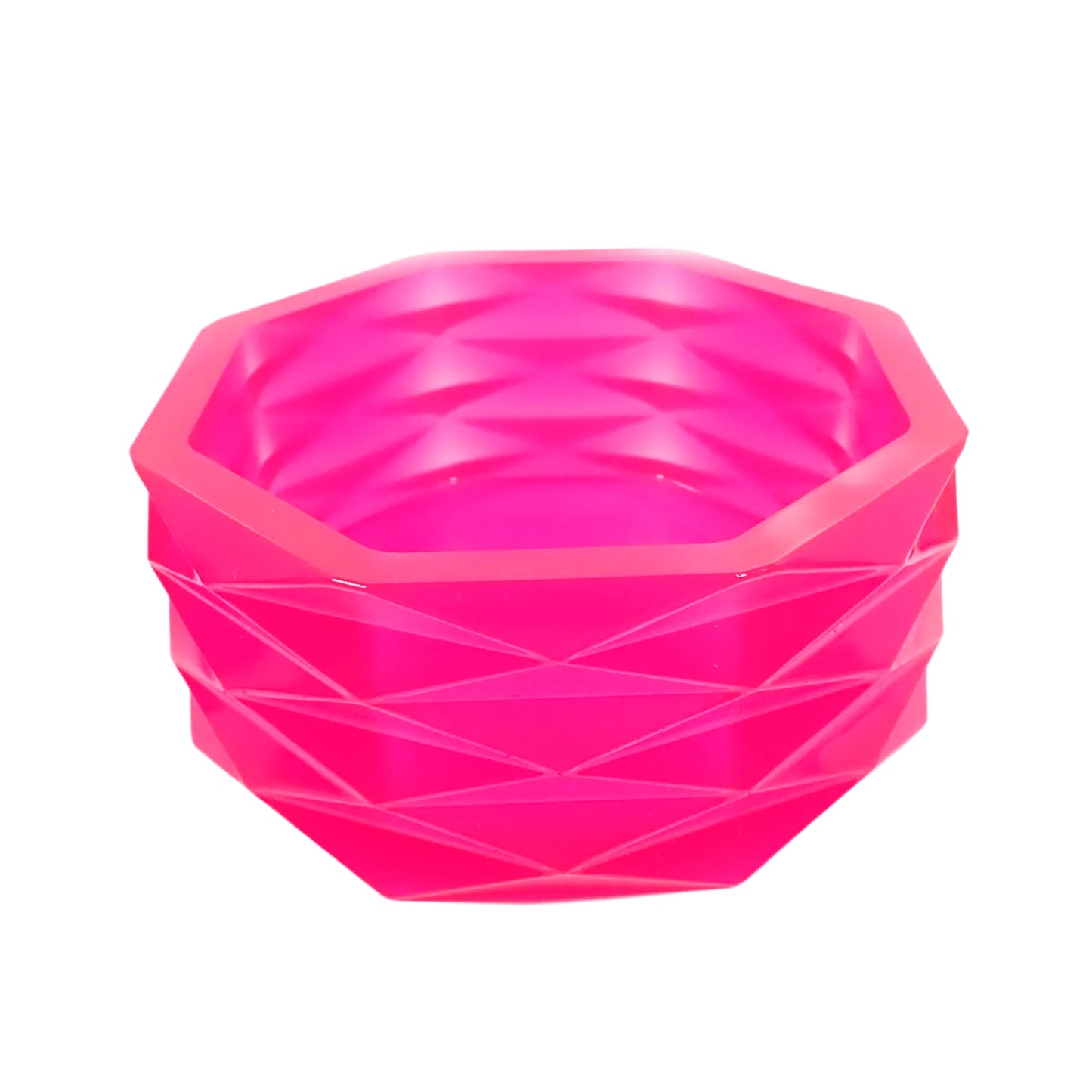 Angled side view of the handmade neon pink resin geometric bowl. It has an overall octagon shape with faceted diamond shapes all the way around the outside of it. The resin is shiny and semi translucent in a bright neon pink color. Great for using as a succulent planter pot, as part of your table centerpiece display, or just to add to your home decor. 