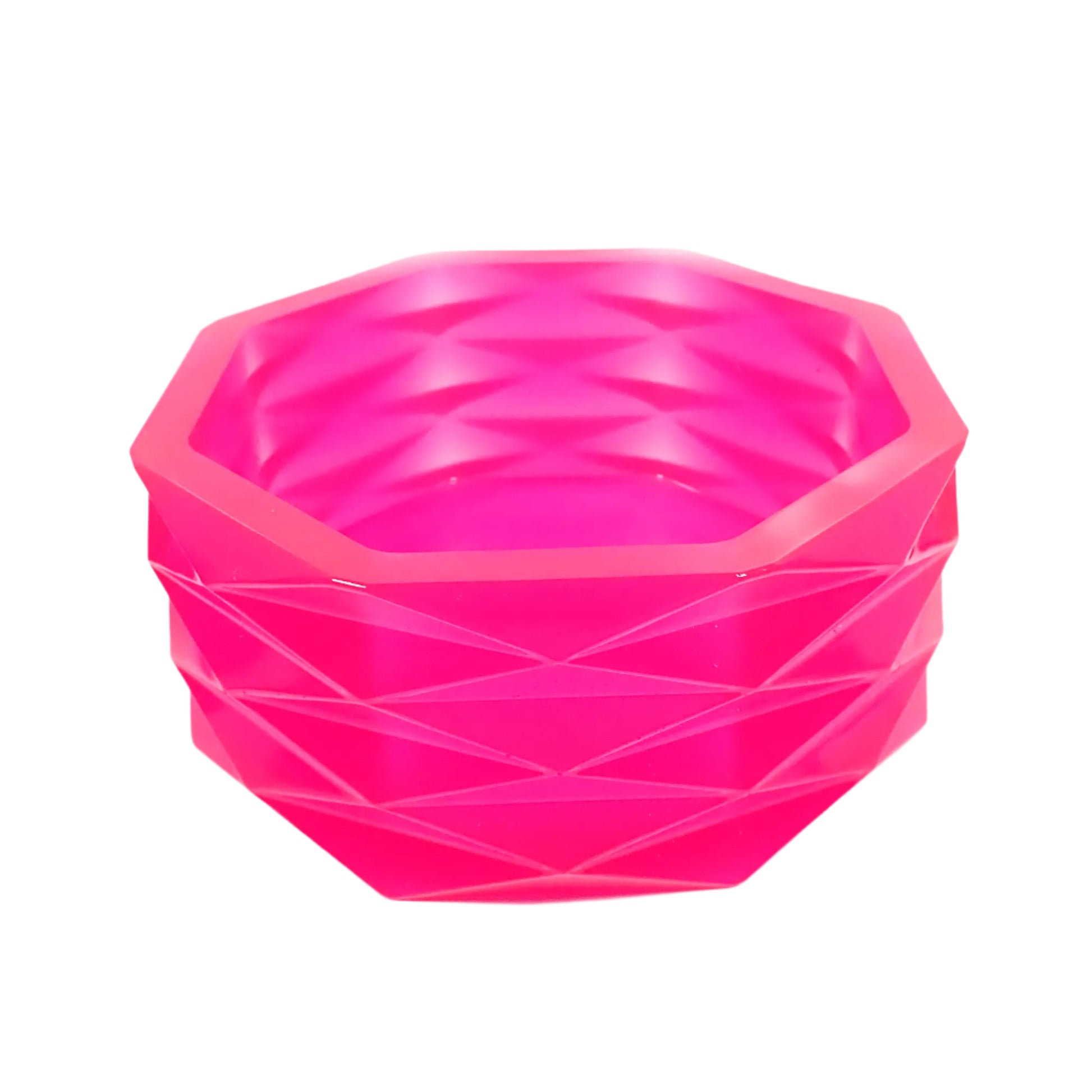 Angled side view of the handmade neon pink resin geometric bowl. It has an overall octagon shape with faceted diamond shapes all the way around the outside of it. The resin is shiny and semi translucent in a bright neon pink color. Great for using as a succulent planter pot, as part of your table centerpiece display, or just to add to your home decor. 