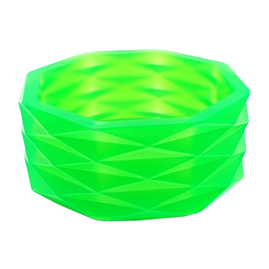 Angled side view of the handmade neon green resin faceted octagon bowl. It has an overall octagon shape with a faceted diamond shape pattern all the way around the outside. The resin is shiny and semi translucent in a bright neon green color that has hints of yellow where the light is passing through it. Great as a trinket bowl, succulent planter pot, as part of your table centerpiece, or just to add to your UV fluorescent home decor.