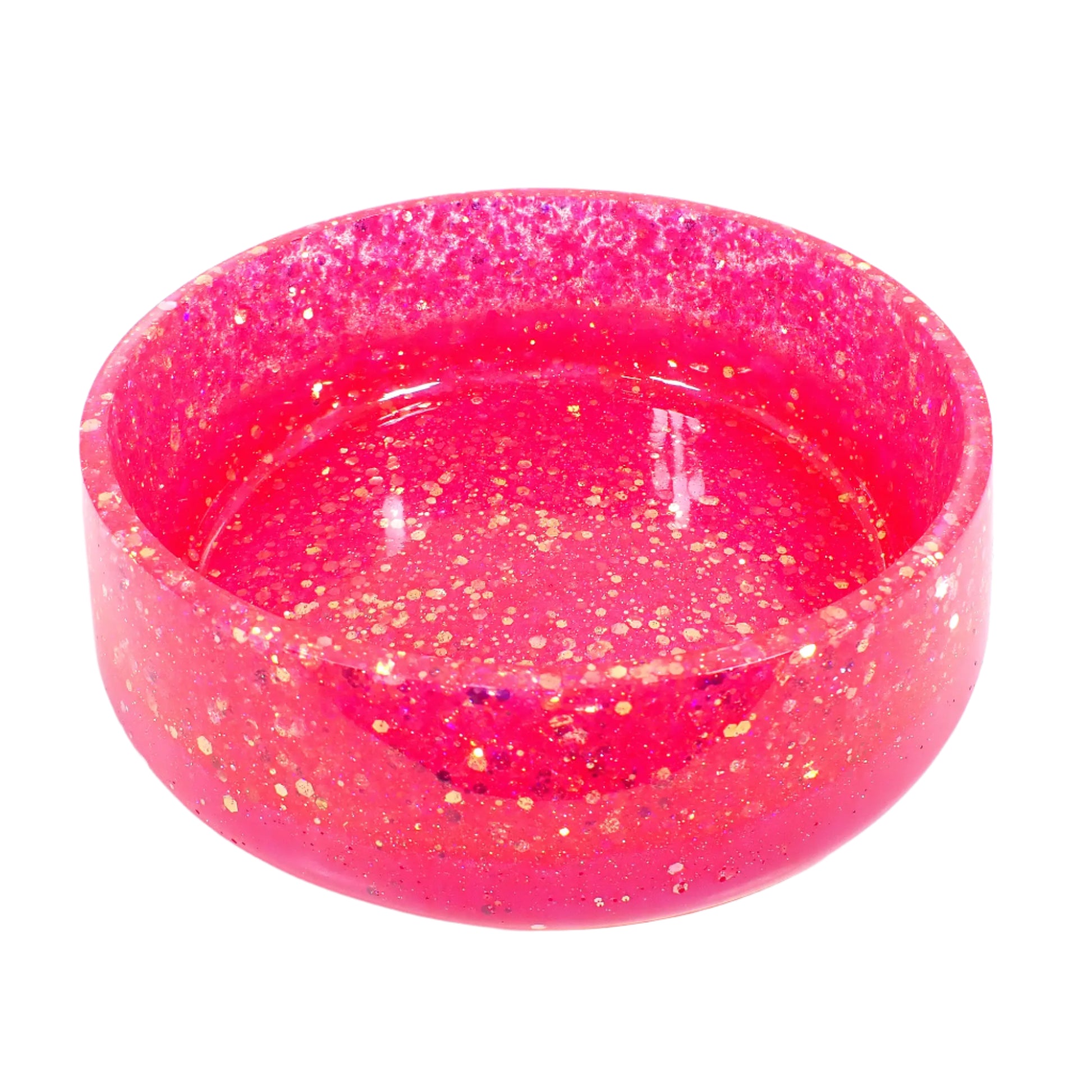 Angled view of the large handmade resin bowl. It's round with a slightly flared out bottom. There is chunky iridescent pink glitter around the top and an area of bright pearly pink resin at the bottom.