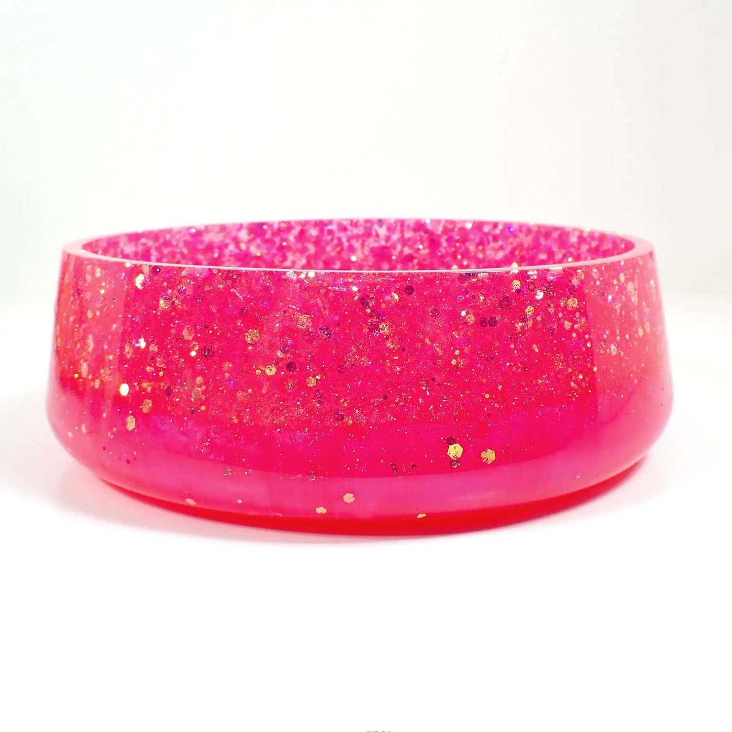 Side view of the large handmade resin bowl. Here it can be seen that a larger portion of the top part of the bowl is sparkly glitter and there is a smaller sized band of bright pearly pink resin on the bottom.