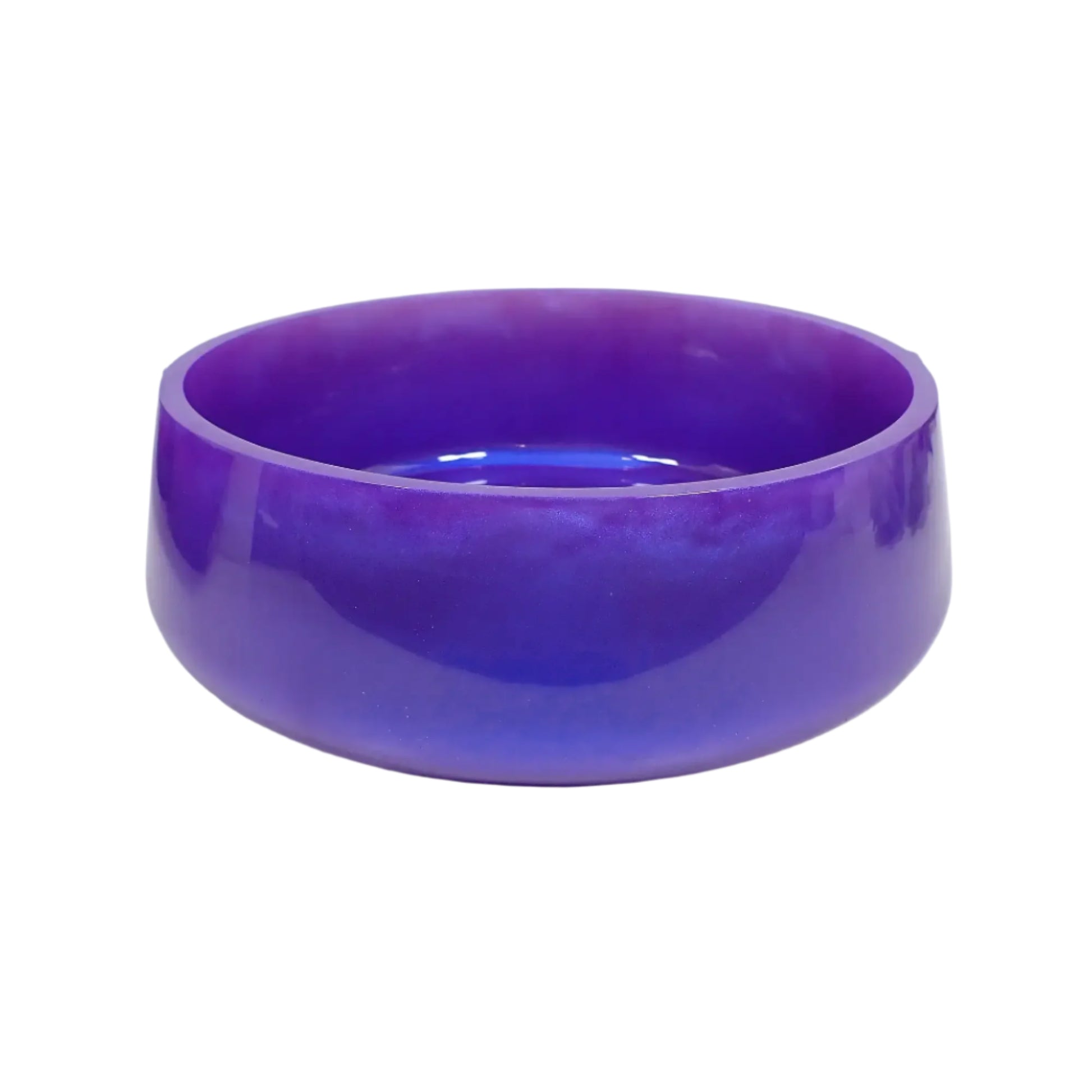 Angled side view of the handmade resin decorative bowl. It has a large round shape with a slightly flared bottom. The resin is shiny and opaque in a pearly iridescent purple color that has flashes of blue as the light hits it. Great piece to use as part of your table centerpiece home decor.